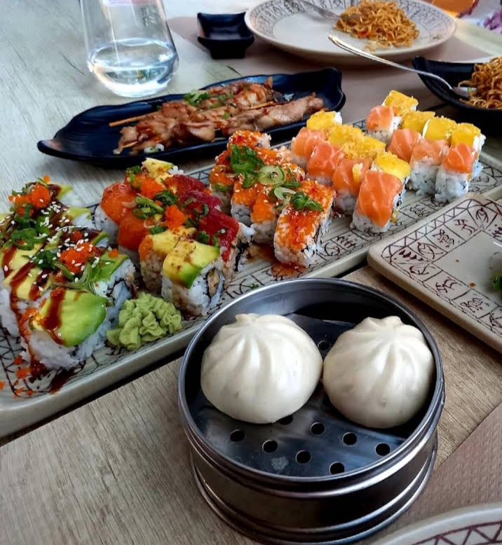 Tisch eines asiatischen Buffets mit gemischten Rollen, Yakitori, Dampfbrötchen und Nudeln